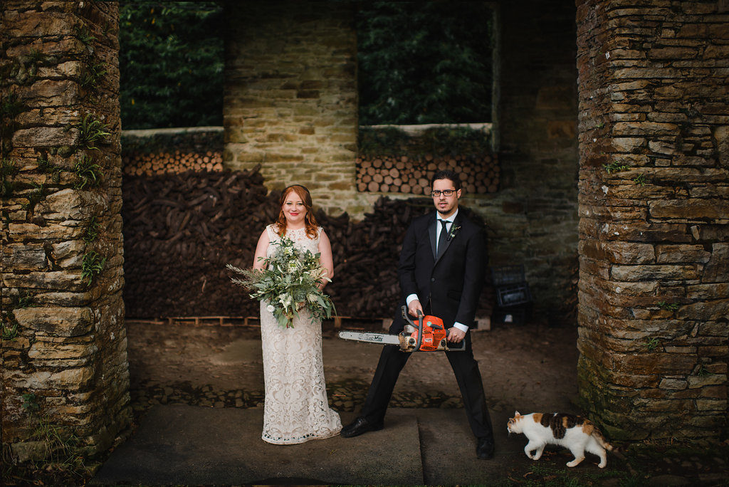 destination wedding in a barn Aislinn Events groom with chainsaw and bride with bouquet