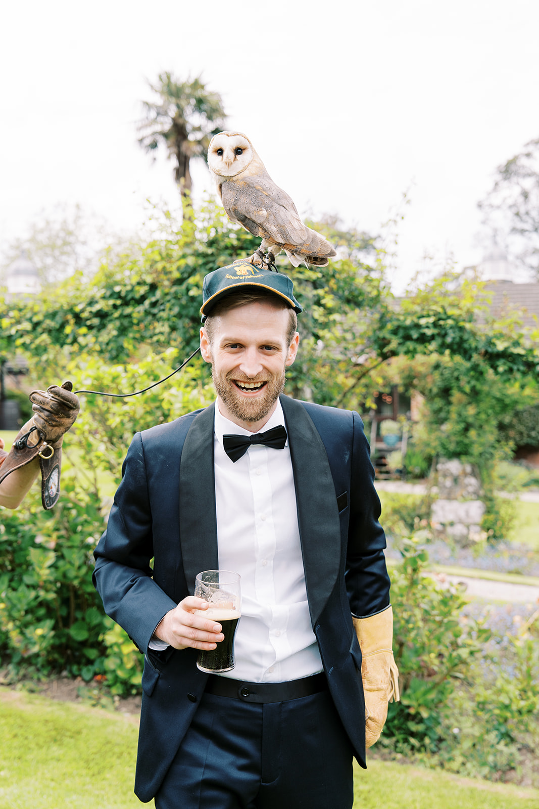 a groom with a pint of Guinness at his Boston to a Dromoland Castle Hotel wedding with an owl on his head