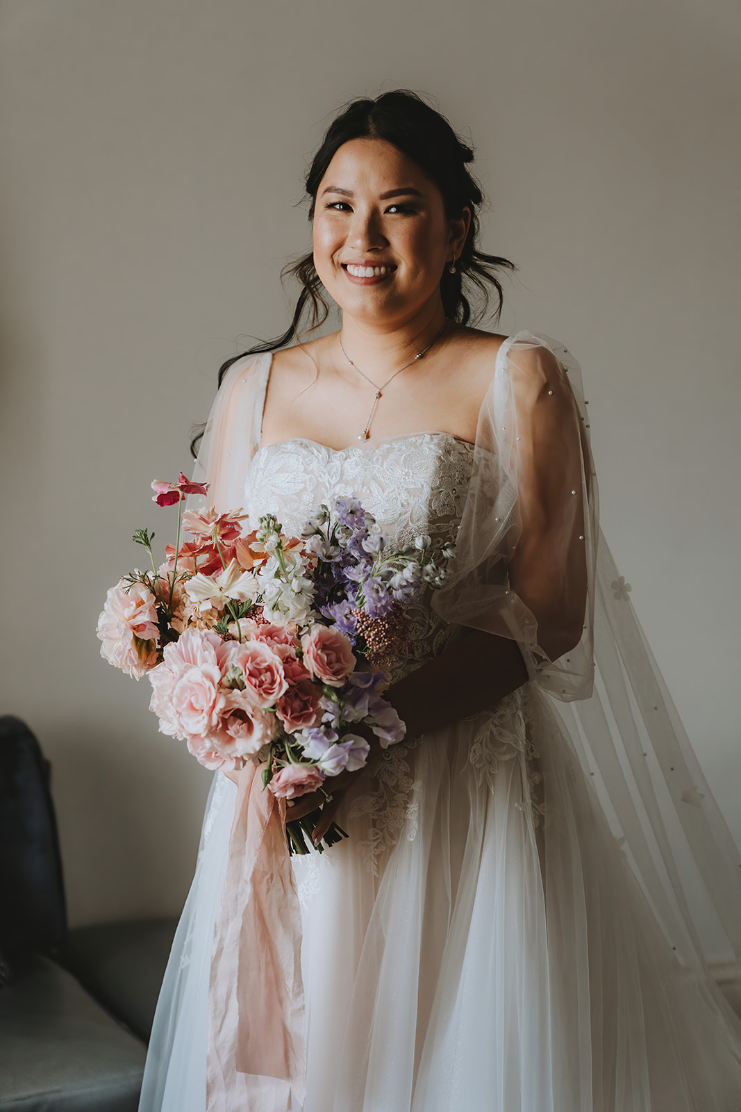 bride with a full bouquest of peach and lilac inspired flowers
