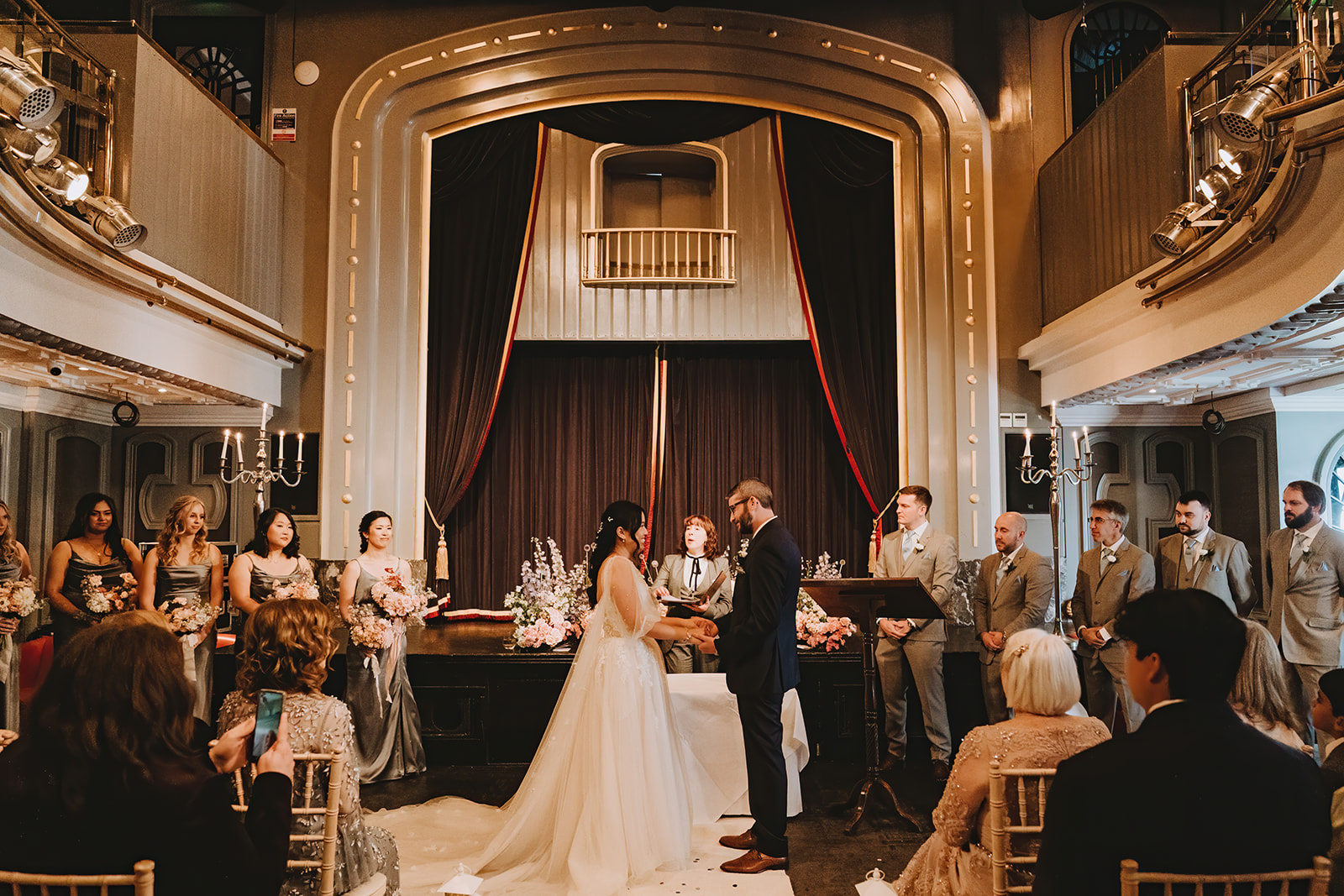The Ceremony: Hosted in the uniquely atmospheric Set Theatre, Langtons Kilkenney bride and groom hlding hands looking into each other eyes and sharing their vows