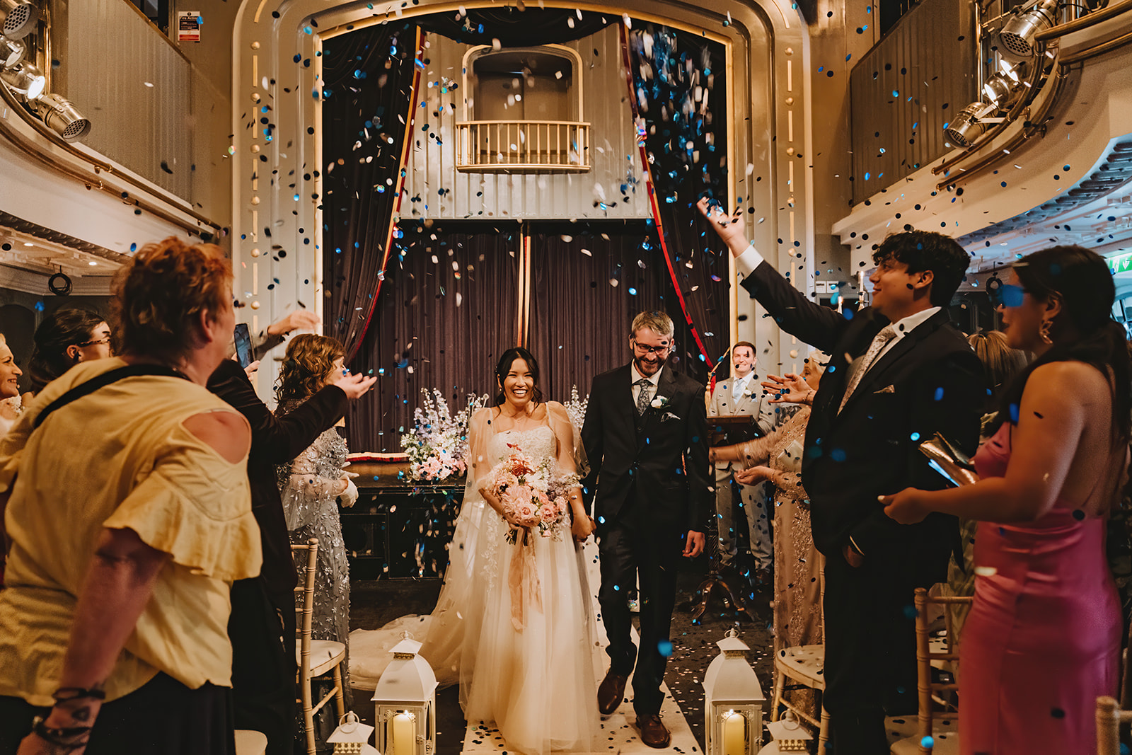 The Ceremony: Hosted in the uniquely atmospheric Set Theatre, Langtons Kilkenney bride and groom holding hands walking down the aisle and having confetti thrown over them