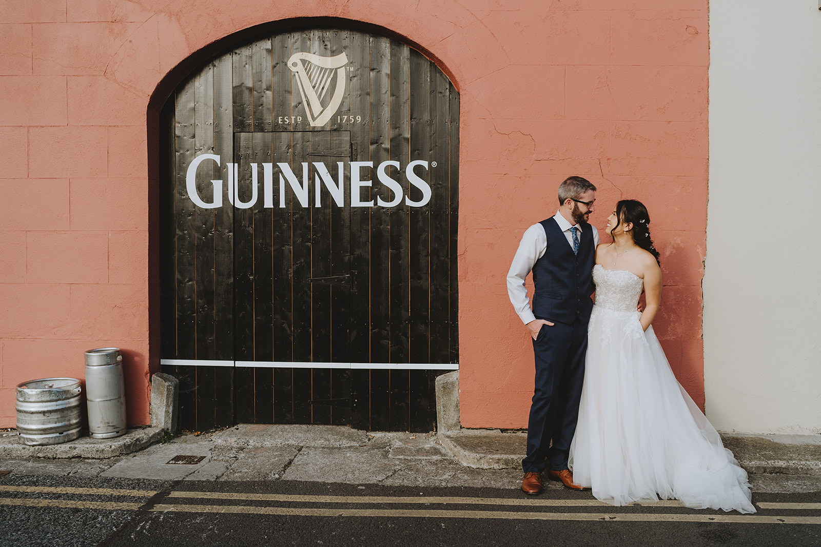 bride and groom outside a bar delivery door with name guiness on iot and a red wall behind them